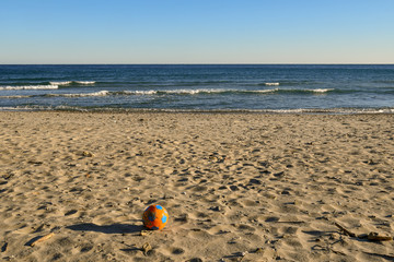 Orange ball on the sandy beach shore, Alassio, Liguria, Italy