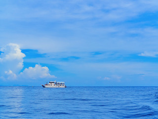 Pleasure boat with tourists is in the sea against the sky with clouds