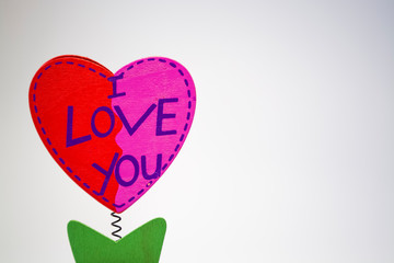 St. Valentine's Day. Red wooden heart with the inscription "I Love You". On a spring with a clothespeg. As a flower in a pot. On a white background.