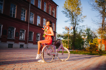 Latin woman in pink dress with flowers and pink bicycle.