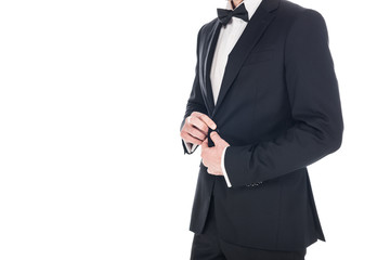 Obraz na płótnie Canvas cropped view of man posing in black elegant tuxedo and tie bow isolated on white