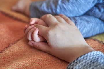 Baby holds her mom's hand while sleeping