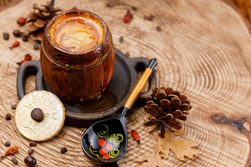 A barrel with fresh fragrant honey and a painted wooden Russian spoon on a wooden saw cut with pine cones.