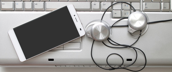 Laptop, smartphone, headphones. Gray background, frontal composition