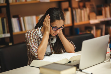 Female student study in the school library.She using laptop and learning online for university exam.