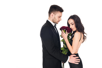tender couple in black clothes posing with red roses on valentines day, isolated on white