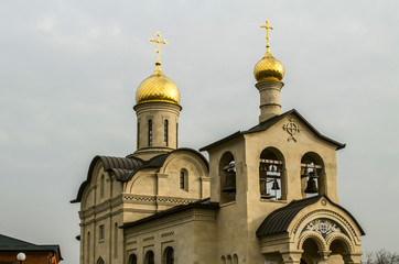 Fototapeta na wymiar Golden domes with crosses over the Orthodox Church of the Life-giving cross of the Lord behind in Yerevan on Admiral Isakov Avenue