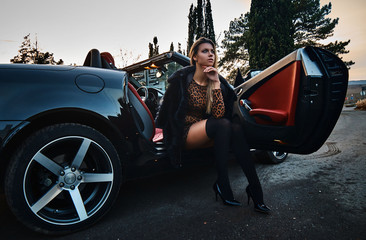 Young sexy blonde in a dress posing in a convertible car