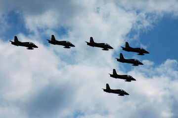 Terrible and frightening dark silhouettes of military jets in the blue sky. Symbol of war.
