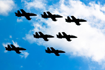 Terrible and frightening dark silhouettes of military jets in the blue sky. Symbol of war.