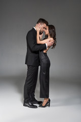 beautiful elegant couple in black clothes embracing on grey