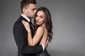 beautiful elegant couple in black clothes hugging isolated on grey