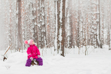 Fototapeta na wymiar Little girl sitting in the winter pine forest