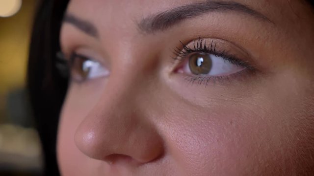Extreme macro closeup of adult caucasian female face with brown eyes looking forward and then at camera