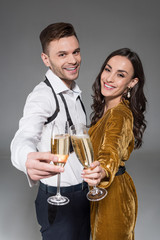 happy couple clinking with champagne glasses isolated on grey