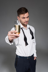 handsome man toasting with glass of champagne isolated on grey