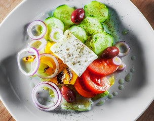 greek salad with cheese, tomato, olive, pepper, onion in white plate