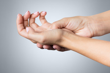 The pain in a female palm on gray background