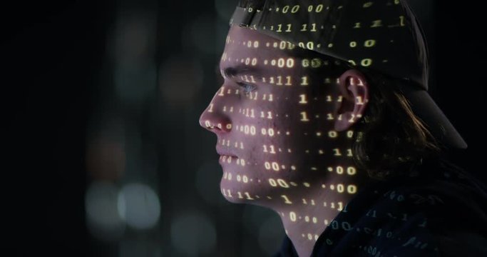 Teenage boy hacking with matrix projected on his face