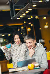 Smiling couple using laptop in cafe