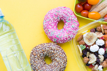 School lunch box. Donat, a bottle of water, candies, baby corns, carrot and tomatoes in green plastic container