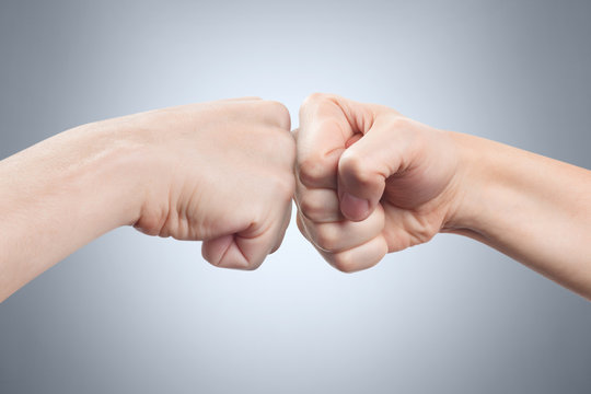 Two fists hitting each other on gray background