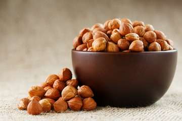 Peeled hazelnuts in a wooden, dark brown cup on a burlap cloth. Super Food, Raw.