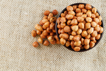 Peeled hazelnuts in a wooden, dark brown cup on a burlap cloth. Super Food, Raw.