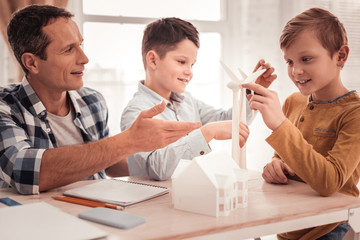 Foster father wearing square shirt teaching his adopted children