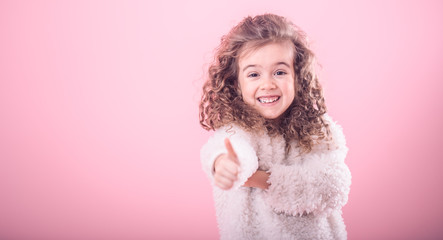 Portrait of girl pointing finger at up on pink