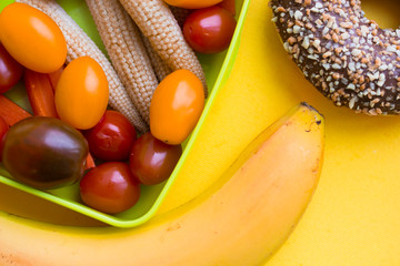 School lunch box. Bread, candies, baby corns, carrot and tomatoes in green plastic container
