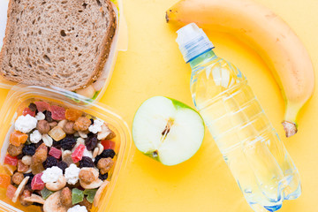 School lunch box. Bread, a bottle of water, candies, baby corns, carrot and tomatoes in green plastic container