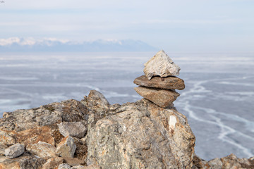 Stone pyramids for spirits on Olhon island. Baikal lake winter landscape