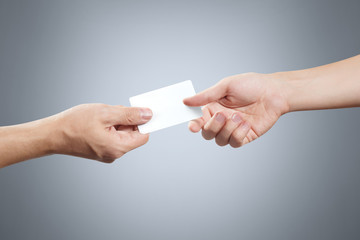 Hand giving a blank card or a ticket/flyer on grey background