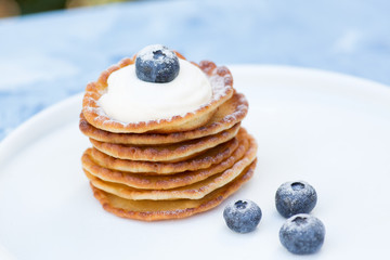 A stack of delicious pancakes with sour cream, raspberries and blueberries on a light background. with copy space