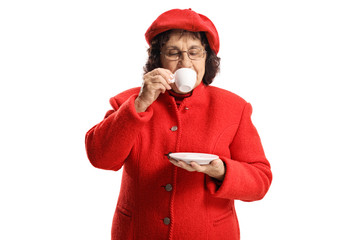 Elderly lady in a red coat taking a sip of espresso coffee