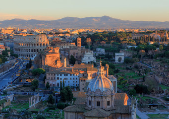 Fototapeta na wymiar Rome, view of the city in the evening, the Forums, the Colosseum and the mountains