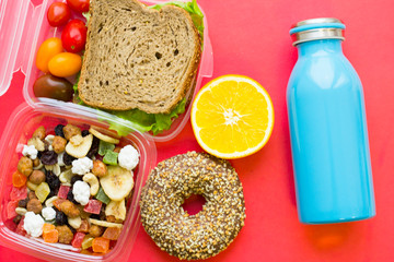 School lunch box. Bread, orange, blue bottle, baby corns, carrot and tomatoes in green plastic container