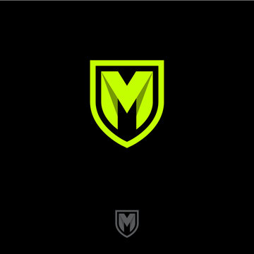 M letter in a shield. M origami monogram consist of green ribbon. Web, UI icon, isolated on a dark background.