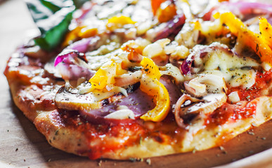 Greek pizza with mushrooms, ham, cheese, onions, pepper on wooden board