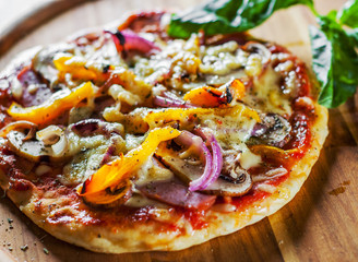 Greek pizza with mushrooms, ham, cheese, onions, pepper on wooden board