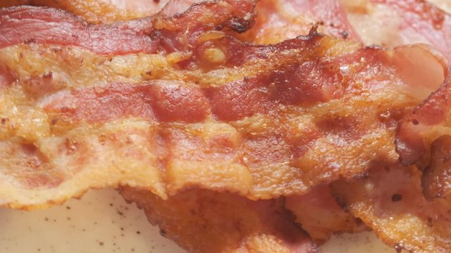 Plate with cooked bacon rashers on table