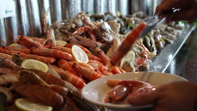 cold seafood buffet line hand taking poached shrimp 4k