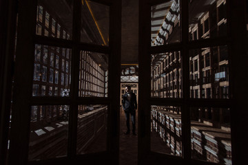 Portrait of Handsome young men in suit and bowtie stands behind opening glass doors. Unusual interior