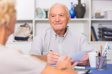 Smiling senior man discussing with wife bills