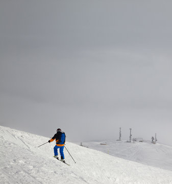 Skier before downhill on slope for freeriding and overcast misty sky