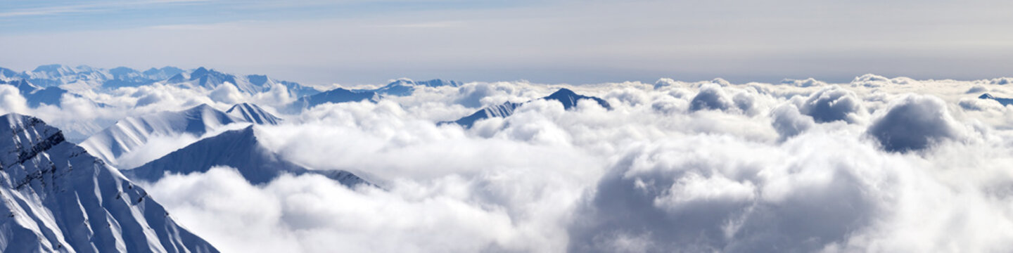 Panorama of snowy mountains covered with sunlight clouds at winter