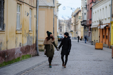Obraz premium a trendy young couple walks in the city, the young woman has shopping bags at her arm and the man a cup of coffee in hand