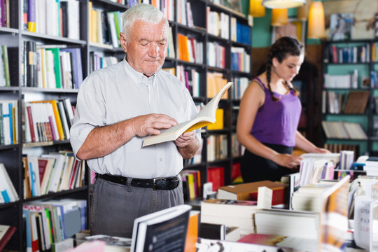 Mature man shopper is choosing book for reading