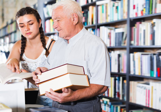 Mature man with young girl are reading books
